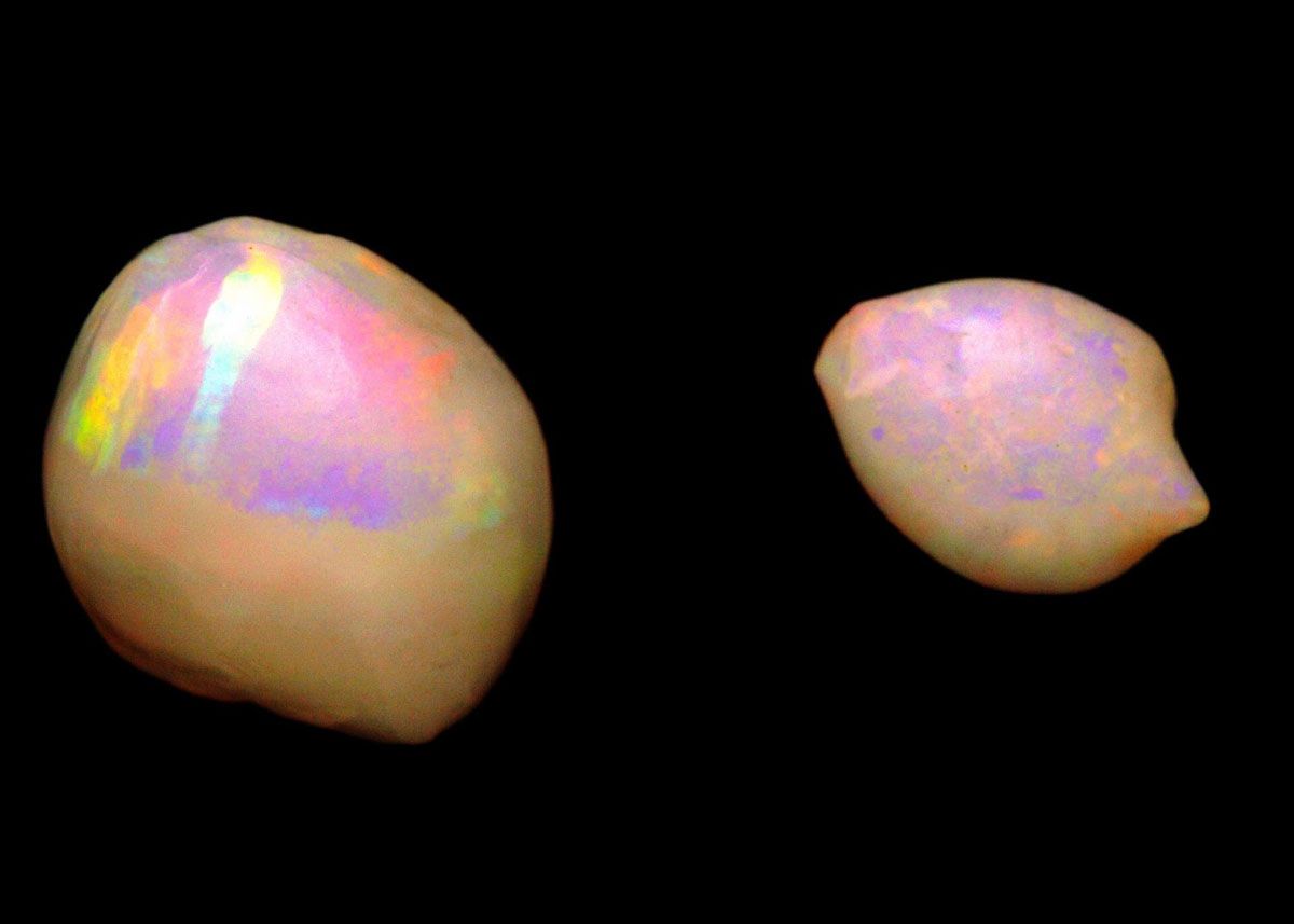 two colorful opalized pearls on black background